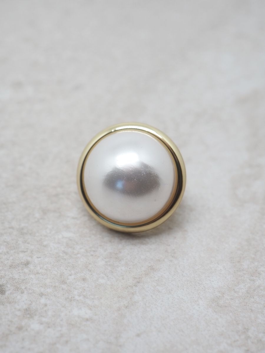 Denne elegante skjerfnålen i gullfarge med en vakker, glansfull off-white perle gir antrekket et sofistikert og feminint uttrykk. Den er liten og nett (ca. 2,5x2,5 cm), men likevel et blikkfang som løfter både skjerf, sjal og yttertøy.