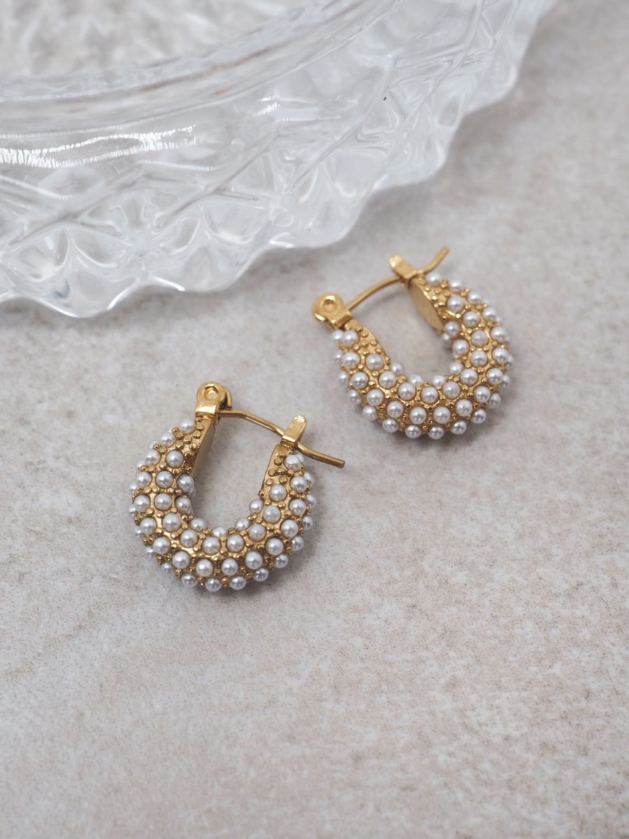 Disse delikate øredobbene er formet som små hestesko og pyntet med klassiske perler for et feminint og stilrent uttrykk. Med en størrelse på 1,3 cm er de perfekte for deg som ønsker et diskret, men elegant smykke til både hverdag og spesielle anledninger.