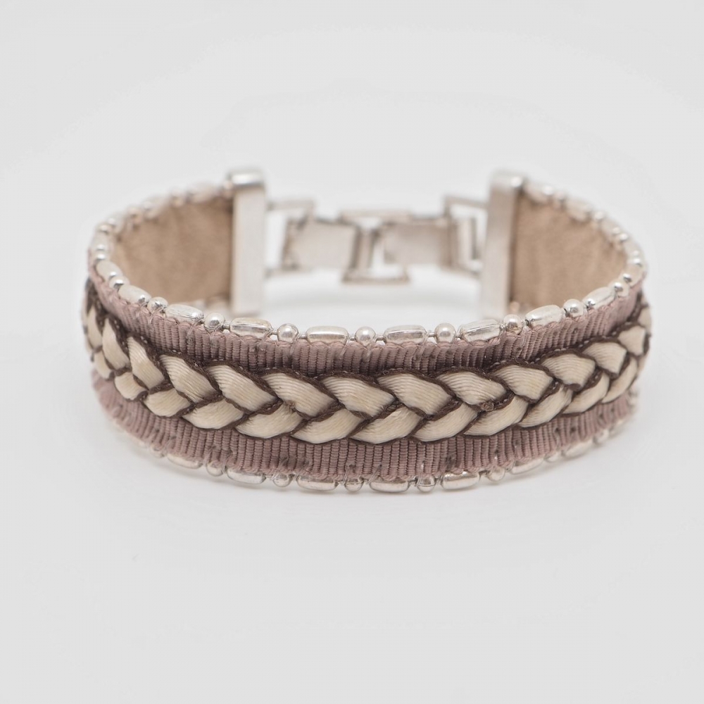 Bomull armbånd som er dekorert med skinnflette og sølvperler.

Nikkelfritt.