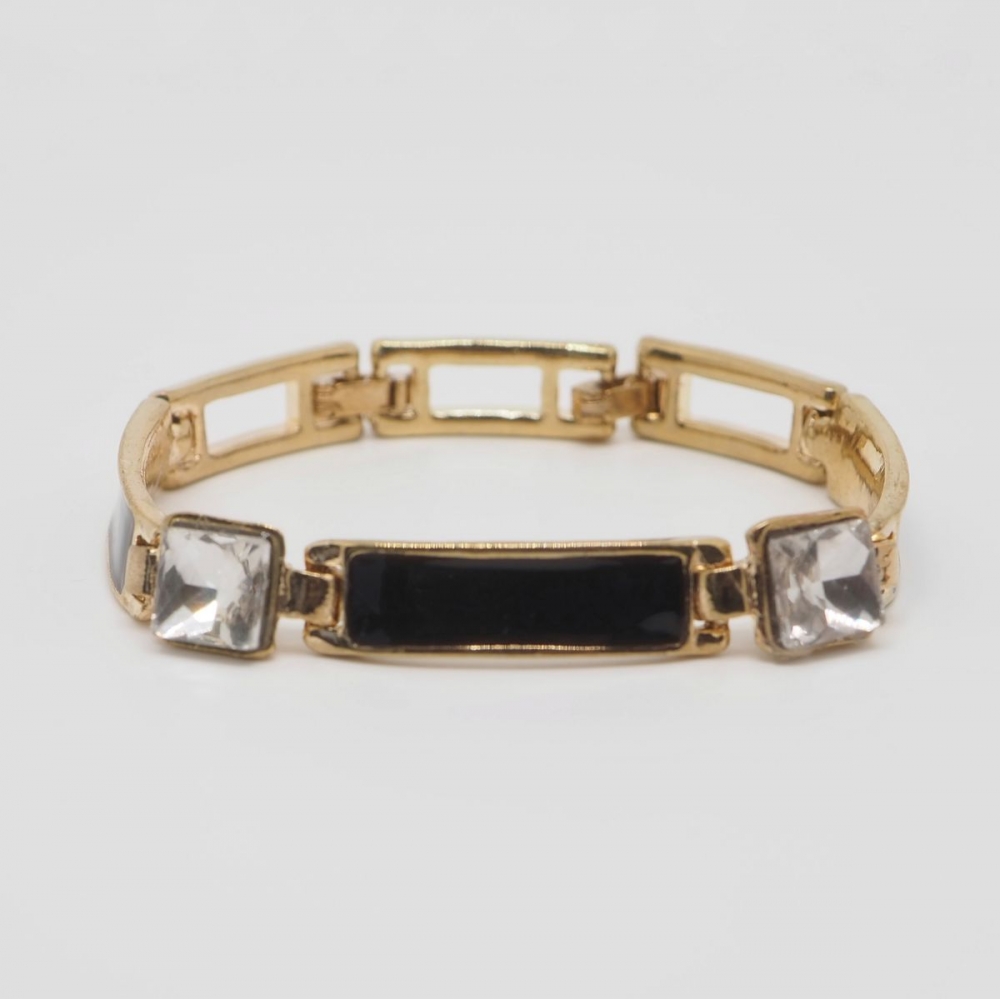 Armbånd i gullfarge med firkantete krystaller og emaljerte detaljer i svart.

Nikkelfritt.