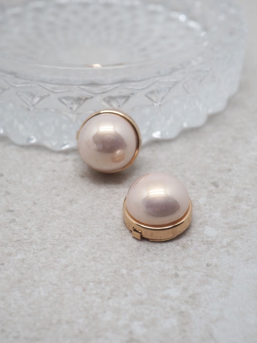 Legg til en søt og feminin detalj med denne gullfargede knappepynten med en klassisk lyserosa perle. Den delikate fargen gir antrekket et friskt og elegant preg, perfekt for både hverdags- og festantrekk.