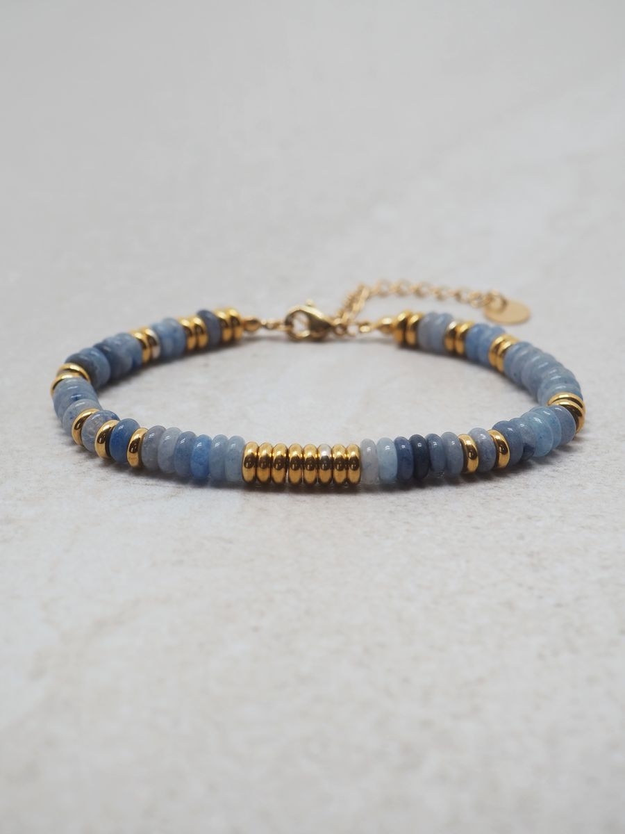 Armbånd i stål forgylt med gull, med naturstener i blåtoner. Lengde 19cm + 6cm forlengelse. Et fint armbånd i fine pastellfarger.

Steinene som blir brukt i dette armbåndet heter blue jade.

Nikkelfri.