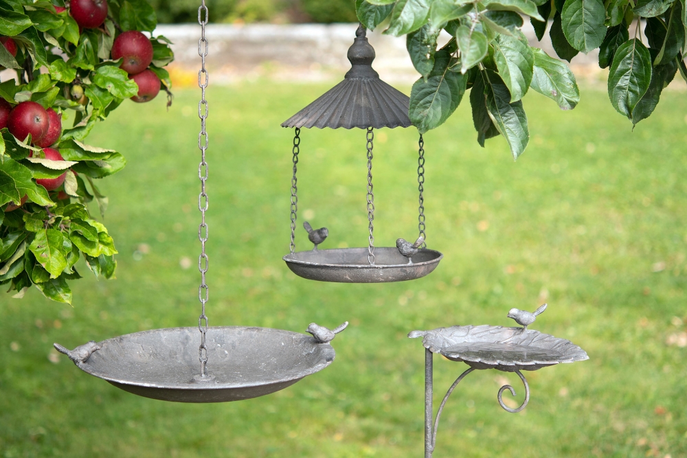 Hengende fuglebad eller matstasjon med tak og søte små fugler. Heng det i et tre i hagen og la fuglene komme på besøk. Laget av metall.
