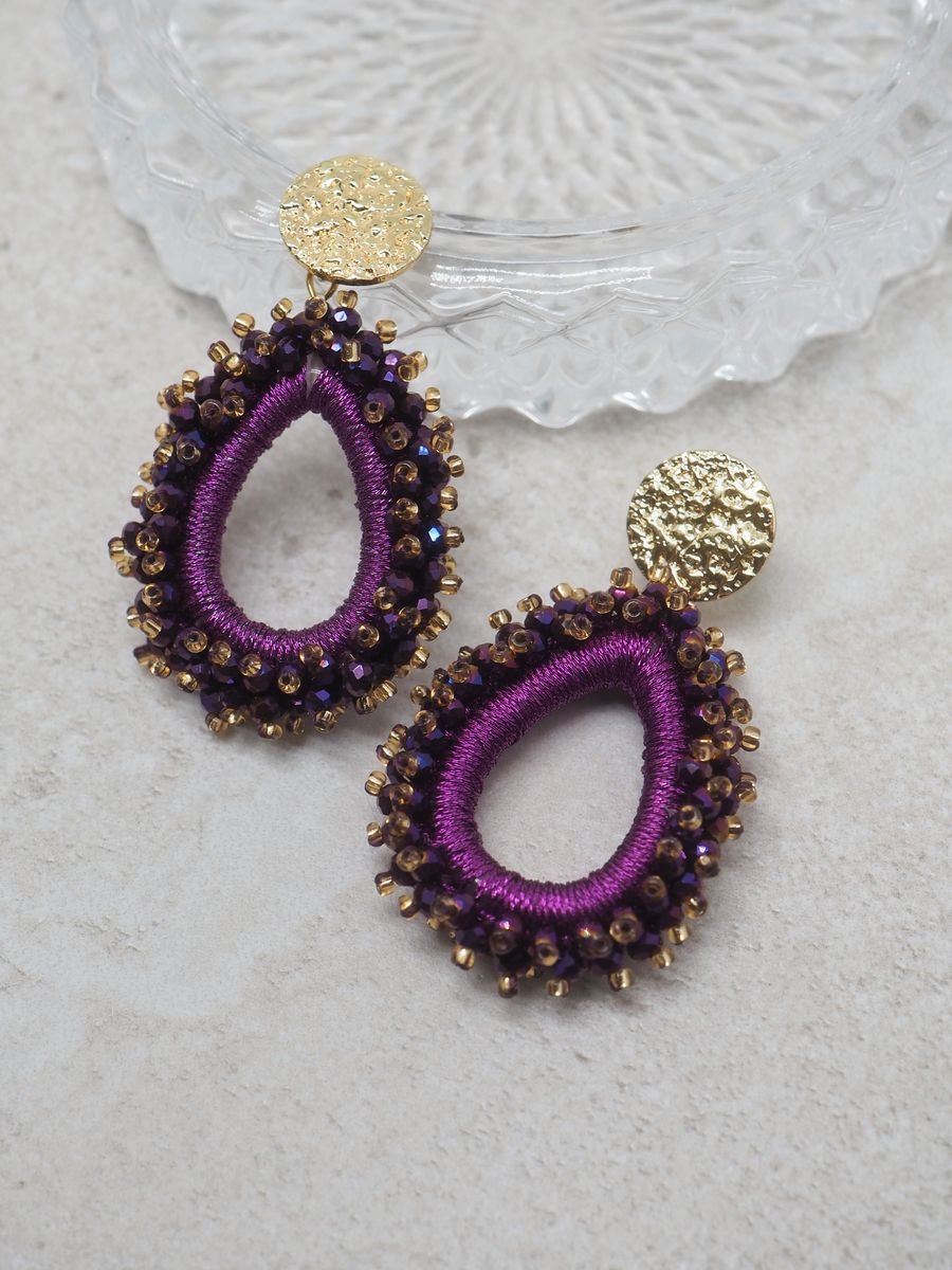 Disse elegante øredobbene i dyp lilla glassperler gir antrekket ditt akkurat den rette mengden glans og glamour. Perfekte til både party og juleselskaper – enten du skal pynte deg litt ekstra til julebordet eller danse deg gjennom nyttårsnatten.