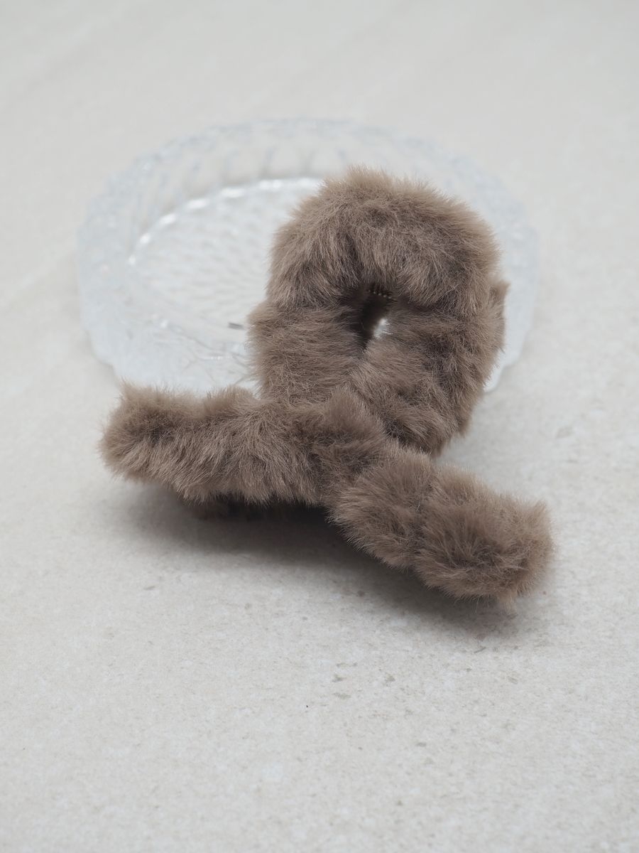 Denne store hårklypen med fuskepels i taupe kombinerer myk luksus med praktisk design.
Den sitter godt i håret og gir frisyren et elegant og moderne uttrykk – perfekt til både hverdags og fest.