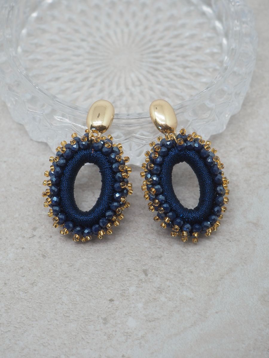 Glitre på festen med disse elegante øredobbene med mørkeblå glasssteiner. Med en lengde på ca 5,5 cm skaper de et iøynefallende og sofistikert uttrykk, samtidig som de er lette og behagelige å ha på gjennom hele kvelden.