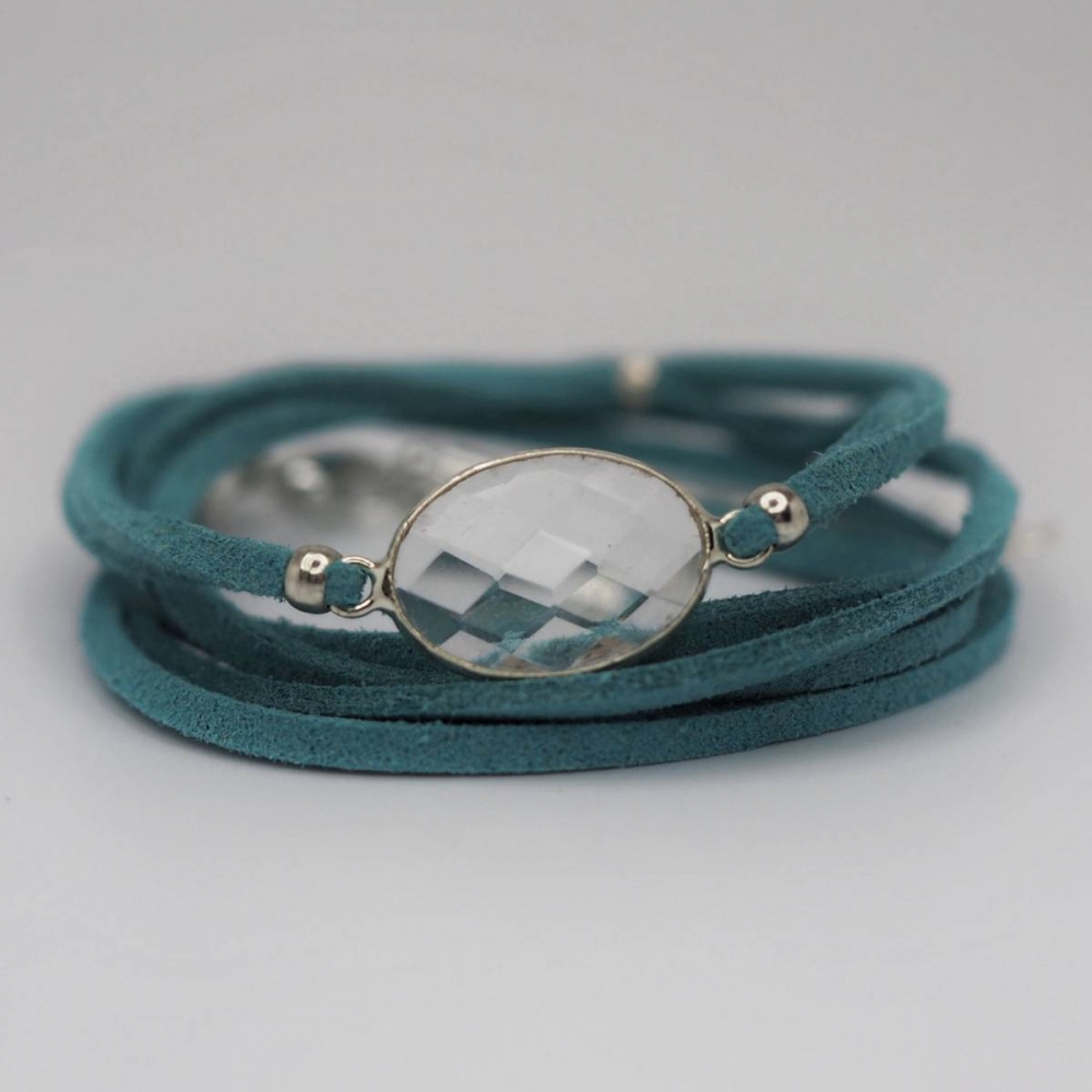 Trendy skinnarmbånd i turkis som man surrer rundt armen. Lenke som gir forlengelse med smykkelås. Mykt skinn som er litt elastisk med klar sten i sølvramme. Fin å bruke alene eller kombinere med andre armbånd. Lengde 51 cm. Nikkelfri.