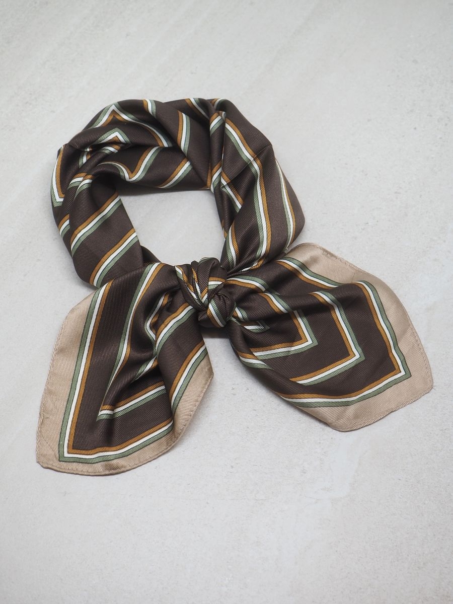 Dette satengskjerfet med brun og beige striper gir antrekket et klassisk og sofistikert uttrykk. Skjerfet er laget av 100% polyester med en glatt og glansfull overflate som føles behagelig mot huden.