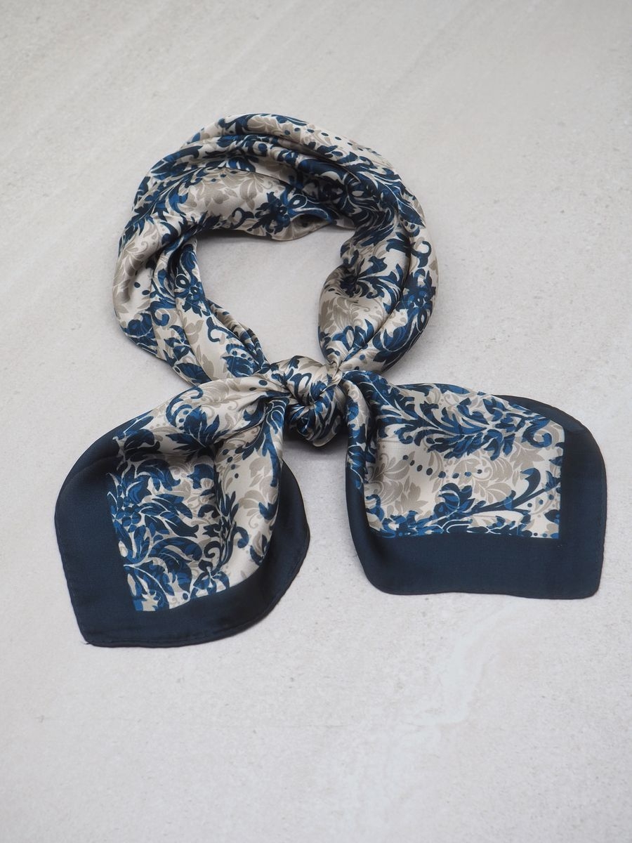 Et vakkert skjerf i sateng med harmoniske blå og offwhite toner – tidløst, elegant og allsidig. Skjerfet er laget av 100% polyester, som gir glatt, myk overflate med lett glans og behagelig følelse mot huden.