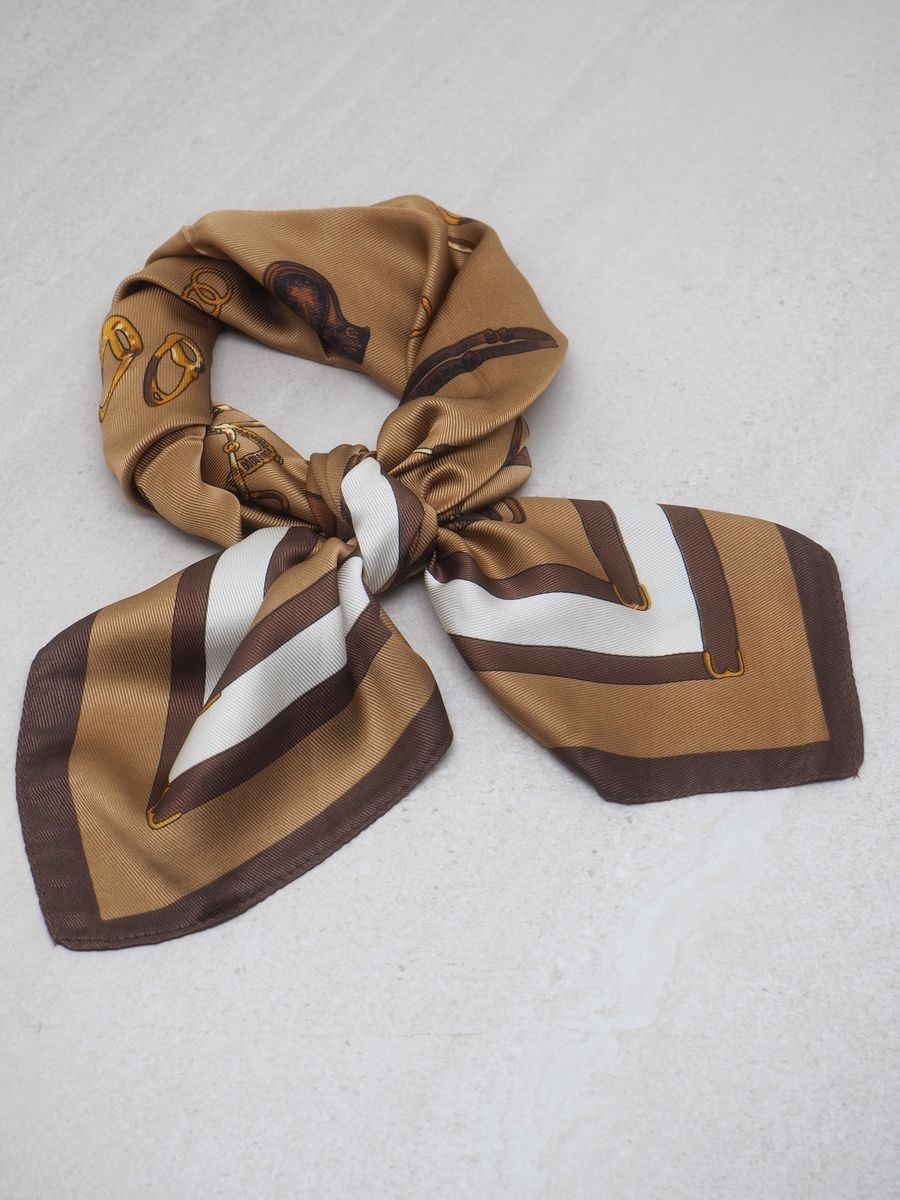 Dette satengskjerfet med brunt hestemotiv kombinerer klassisk eleganse med lekent design. Skjerfet er laget av 100% polyester med en glatt og glansfull overflate som føles behagelig mot huden.