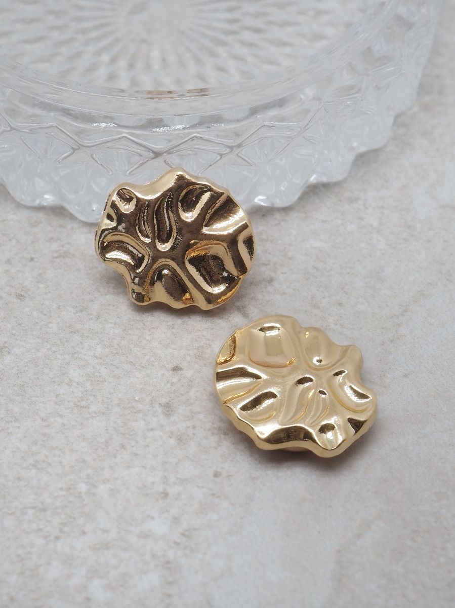 Denne tøffe knappepynten i metall gullfarget, har en oval form med irregulær overflate som gir et rått og moderne uttrykk. Perfekt når du vil gi nytt liv til jakker, strikk, kjoler eller vesker uten å bytte hele plagget. 