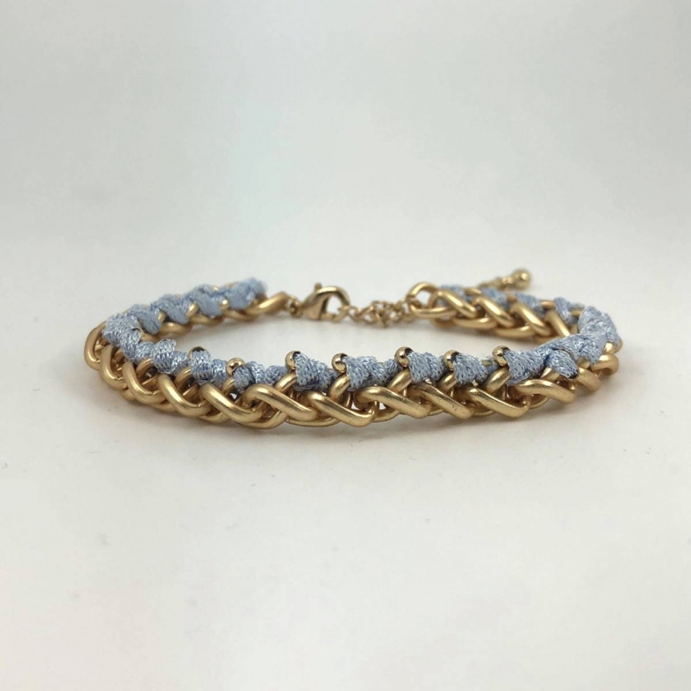 Armbånd i matt gullfarge med lyseblå tråd.

Nikkelfri.