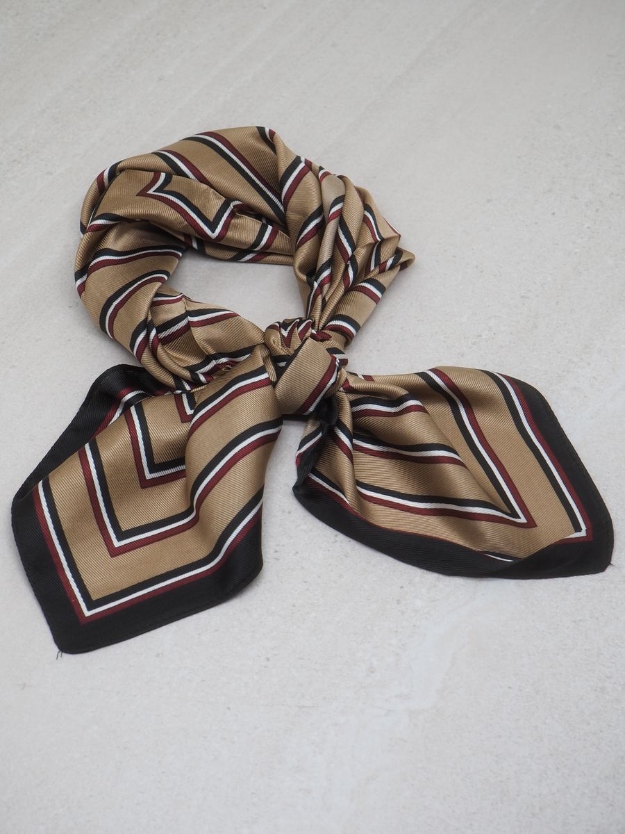 Dette satengskjerfet med beige og svarte striper gir antrekket et klassisk og elegant preg. Skjerfet er laget av 100% polyester med en glatt og glansfull overflate som føles behagelig mot huden.