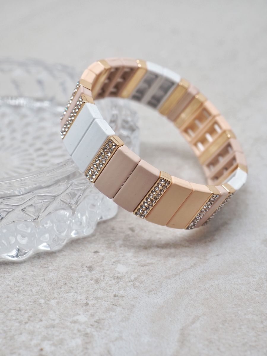 Emaljert strikkarmbånd i gull, hvit og beige fargekombinasjoner. Bredde ca 1,7cm. Nikkelfritt produkt.